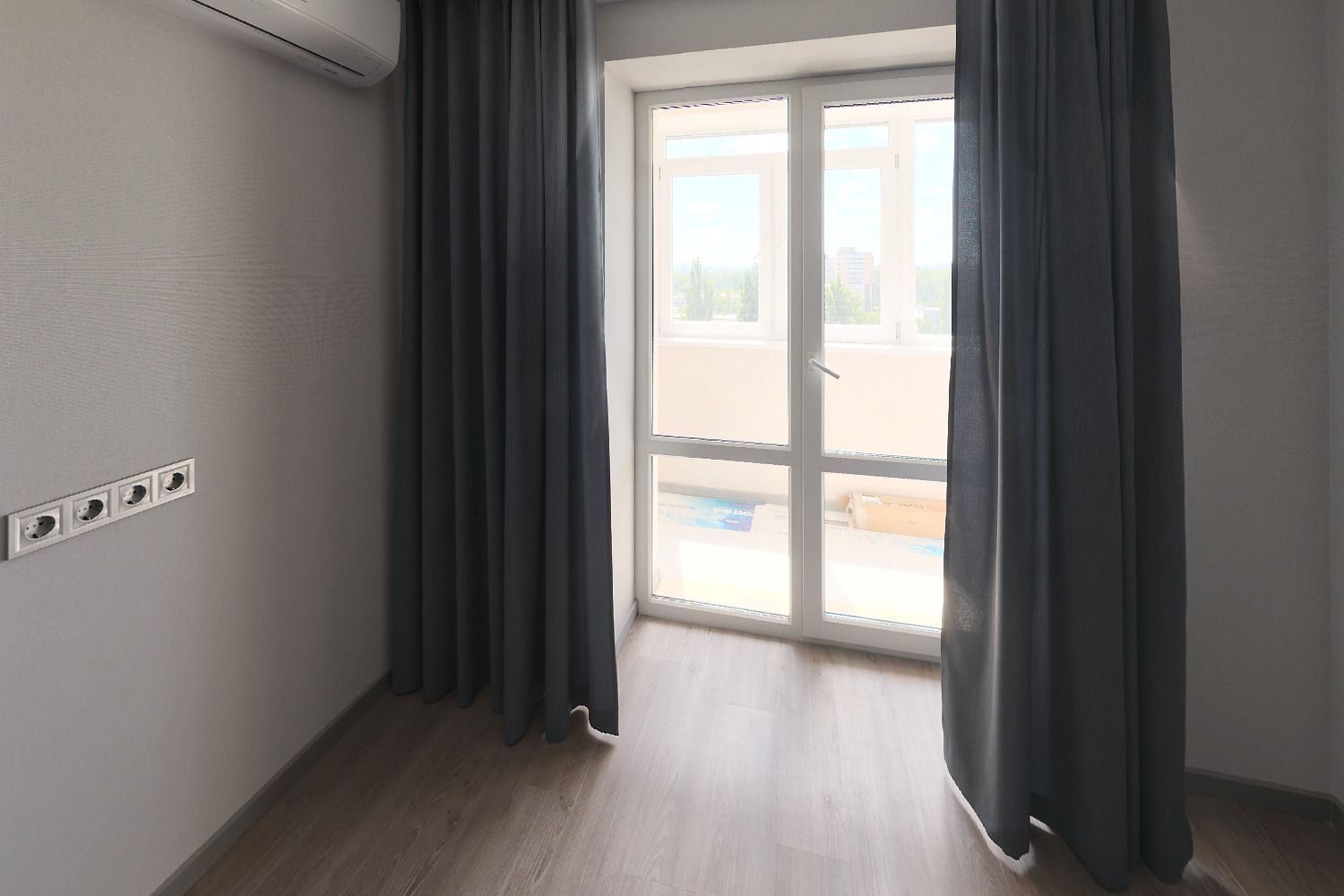Empty primary bedroom with gray walls, dark curtains, a tall glass balcony door and a wood-look floor, before virtual staging